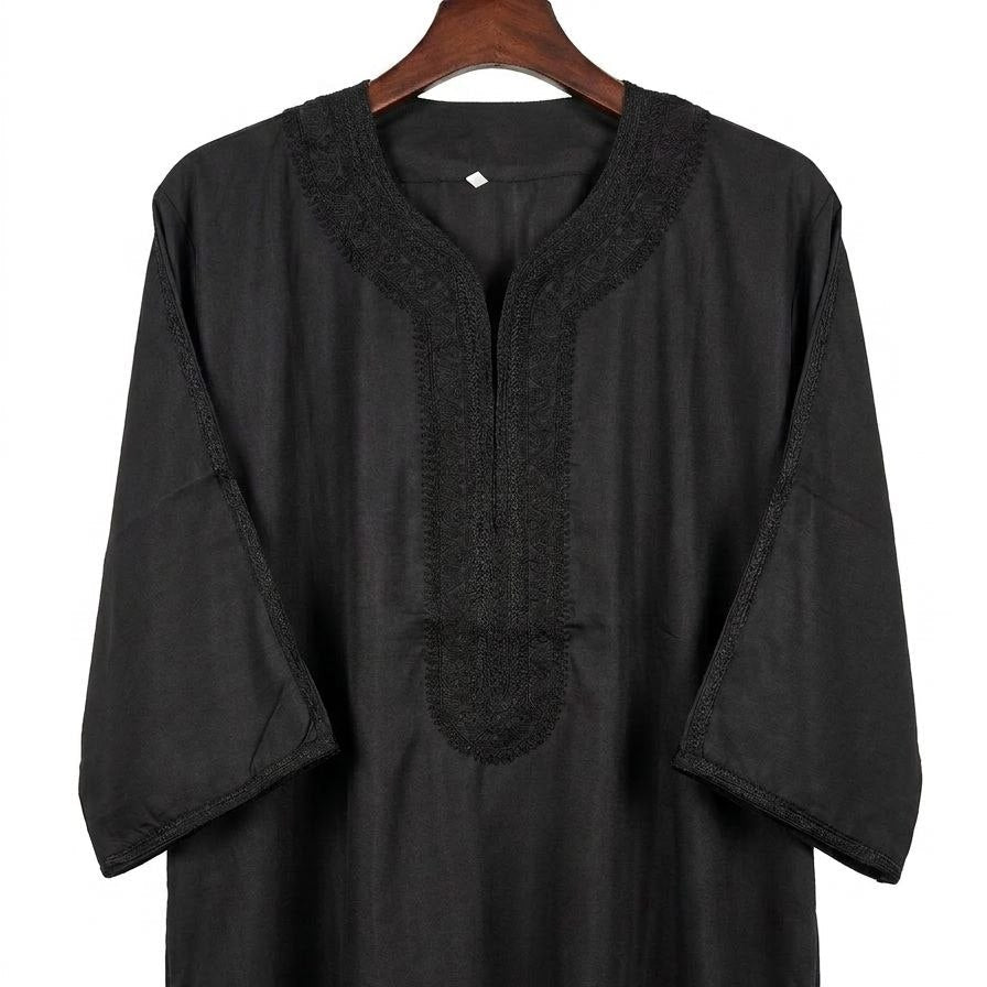 Black long-sleeve garment on a hanger against a white background